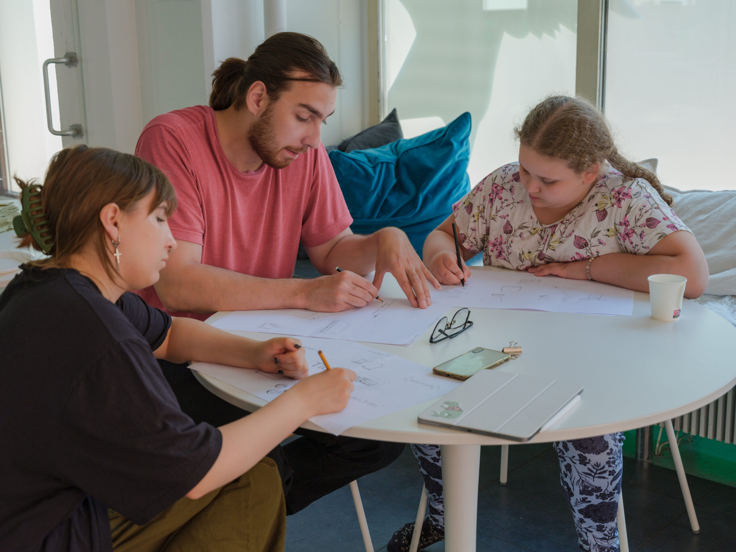 kolme henkilöä työskentelee pöydän ympärillä